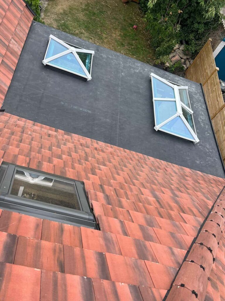 This is a photo taken from the roof ridge looking down a tiled pitched roof on to a flat roof. Works carried out by TRP Roofing Kingswood